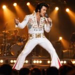 Elvis Presley tribute artist performing on stage in a rhinestone jumpsuit