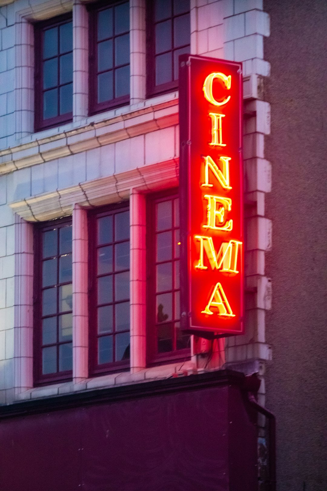 Neon cinema sign at night, representing stylish action movie atmosphere